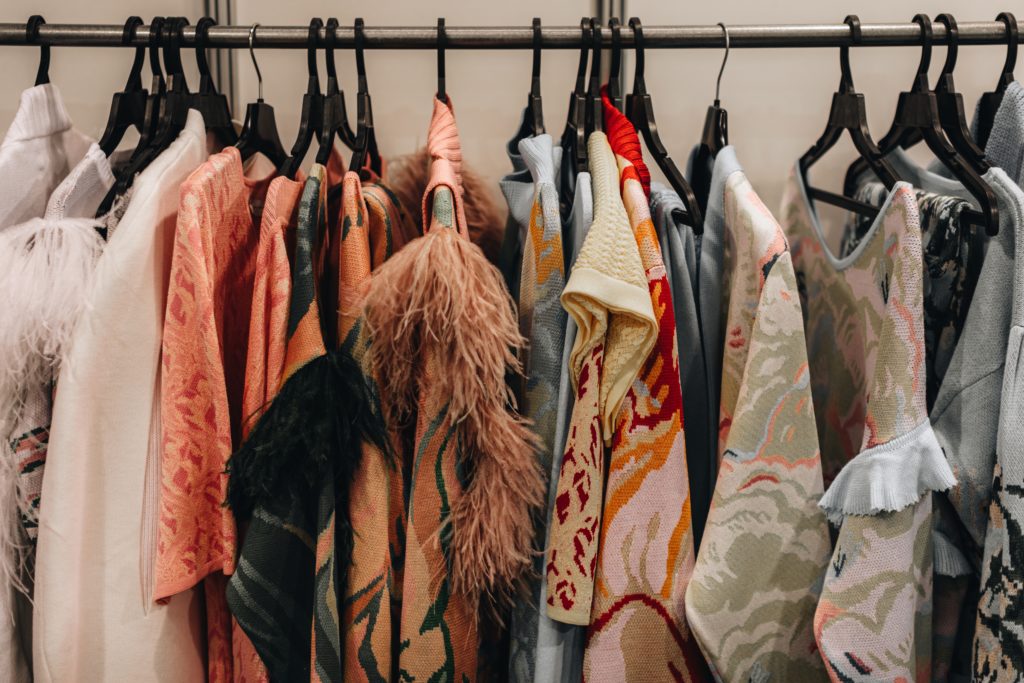 Designer fashion outfits hanging in a row at the backstage of Fashion week