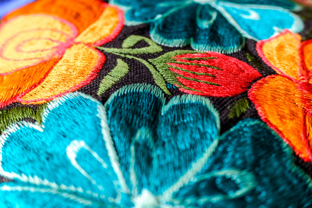 Detail of a colorful embroidery with flower motifs in brightly colored fabrics.